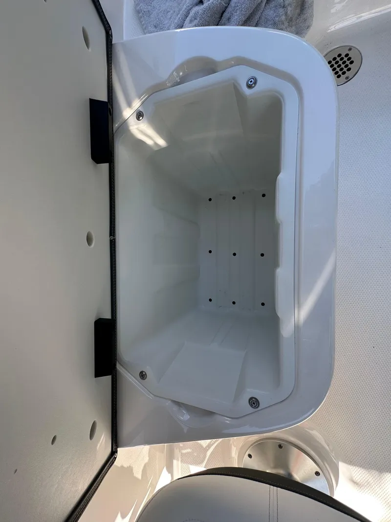Slide: The Image of 2023 Chaparral 270 OSX boat storage compartment, open lid, white interior. - 19