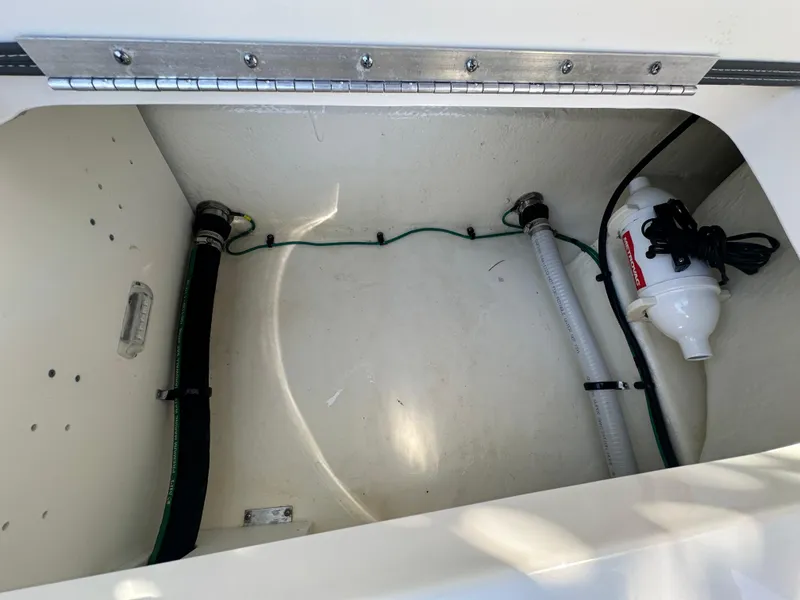Slide: The Image of 2023 Chaparral 270 OSX boat compartment with hoses and pump. - 23