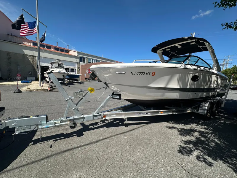 Slide: The Image of 2023 Chaparral 270 OSX boat on trailer, parked outdoors under clear blue sky. - 9