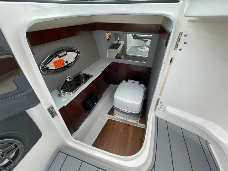 Slide: The Image of 2025 Chaparral 270 OSX boat interior with compact bathroom, sink, and toilet. - 21