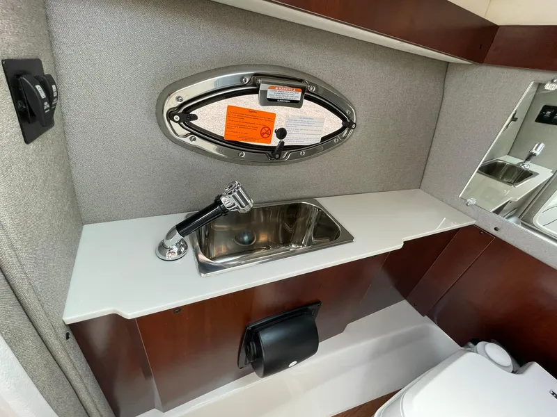 Slide: The Image of 2025 Chaparral 270 OSX boat interior with sink, mirror, and porthole window. - 22