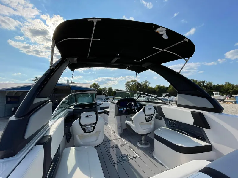 Slide: The Image of 2025 Chaparral 270 OSX boat interior with seating and helm under a sunny sky. - 47