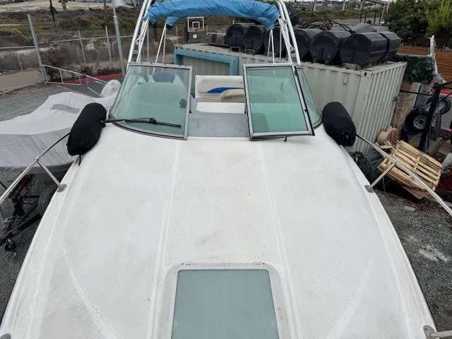 Slide: The Image of 2006 Bayliner 265 SD boat on land, with open windshield and protective covers. - 13
