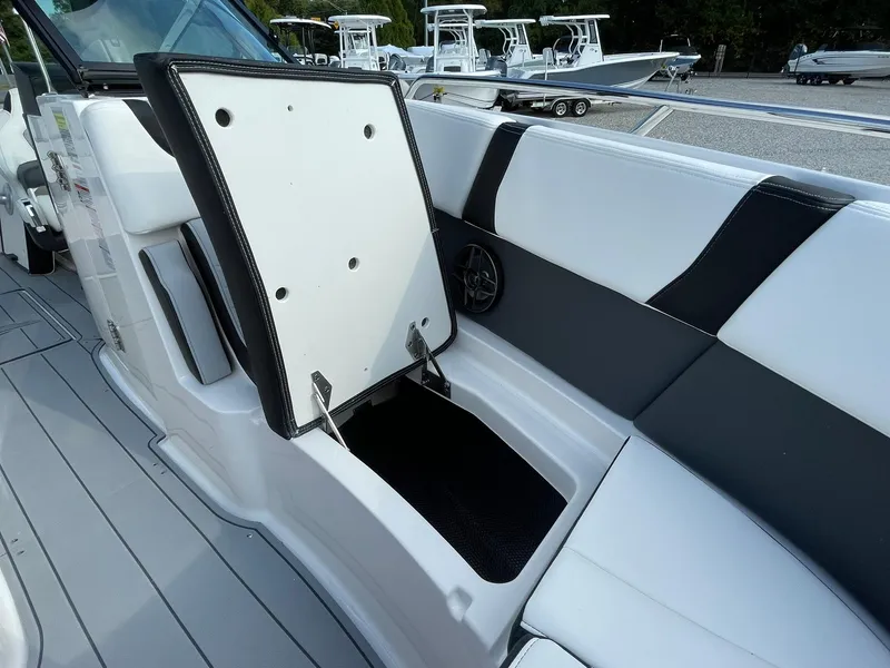 Slide: The Image of 2025 Chaparral 270 OSX boat interior with open storage compartment, showcasing sleek seating design. - 15