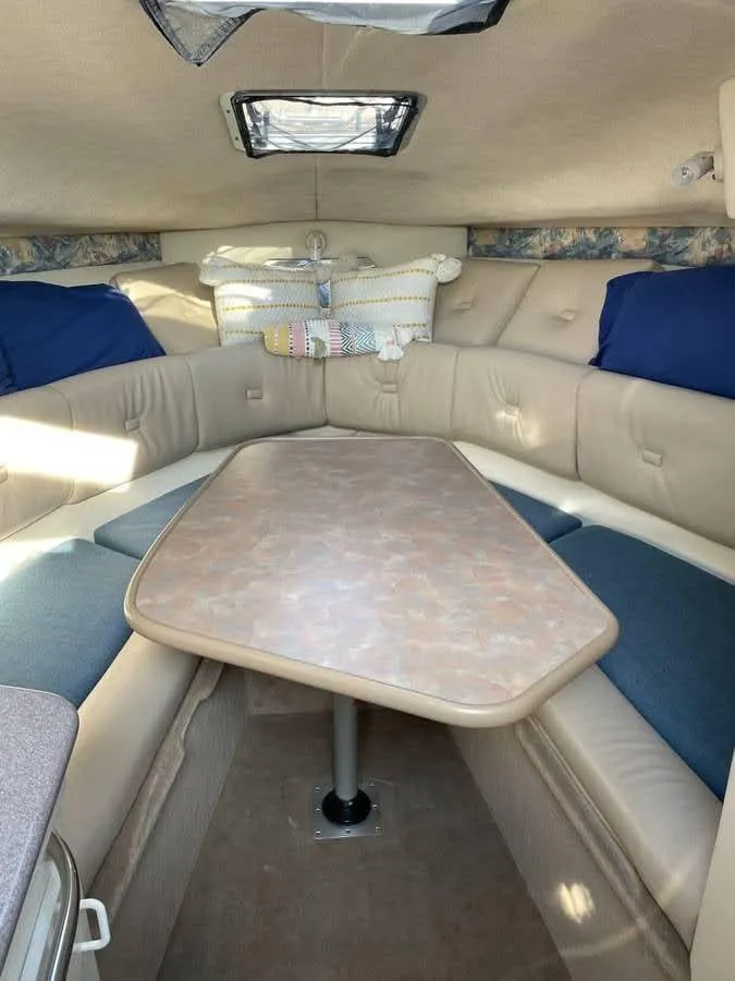 Slide: The Image of 1998 Chaparral 270 Signature cabin interior with table and seating, featuring beige and blue accents. - 13