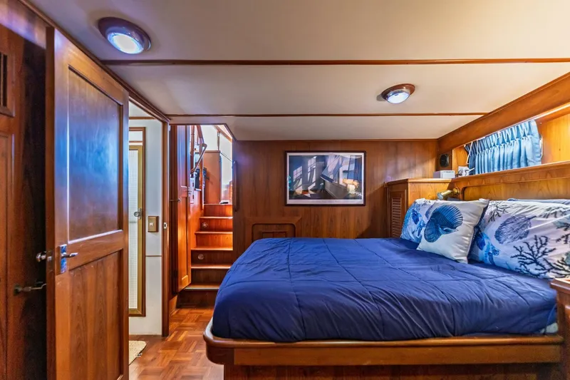 Slide: The Image of Luxurious 1992 DeFever 49 Pilothouse bedroom with wood paneling and blue bedding. - 10