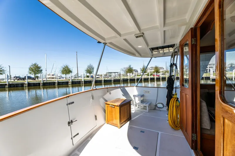 Slide: The Image of 1992 DeFever 49 Pilothouse yacht deck with wooden doors, docked by calm waters. - 16