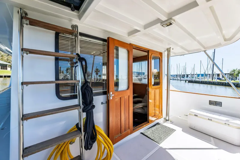 Slide: The Image of 1992 DeFever 49 Pilothouse yacht deck with wooden doors and marina view. - 17