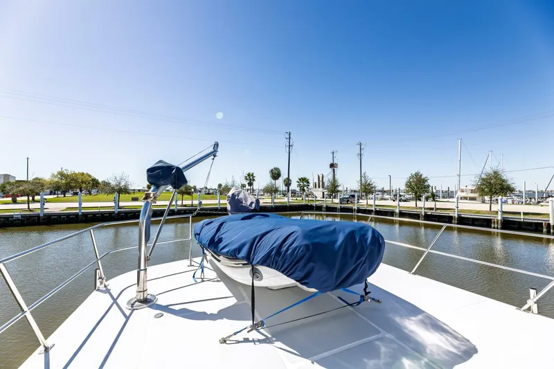 Slide: The Image of 1992 DeFever 49 Pilothouse yacht deck with covered equipment, docked by a calm waterway. - 21