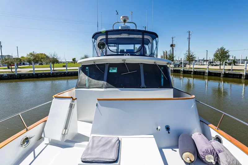 Slide: The Image of 1992 DeFever 49 Pilothouse yacht docked in a serene marina setting. - 32