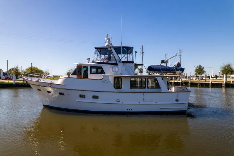 Slide: The Image of 1992 DeFever 49 Pilothouse yacht cruising on calm waters under clear blue sky. - 42