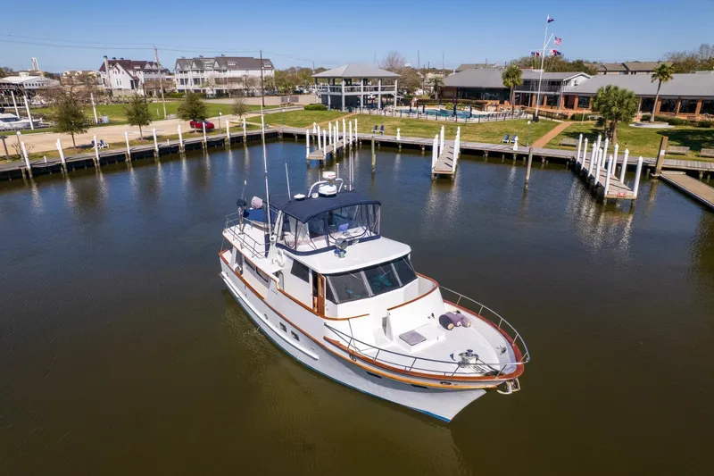 Slide: The Image of 1992 DeFever 49 Pilothouse yacht docked in a serene marina setting. - 45