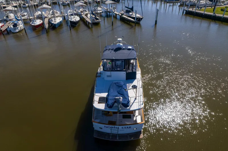 Slide: The Image of 1992 DeFever 49 Pilothouse yacht docked in a marina, surrounded by other boats. - 46