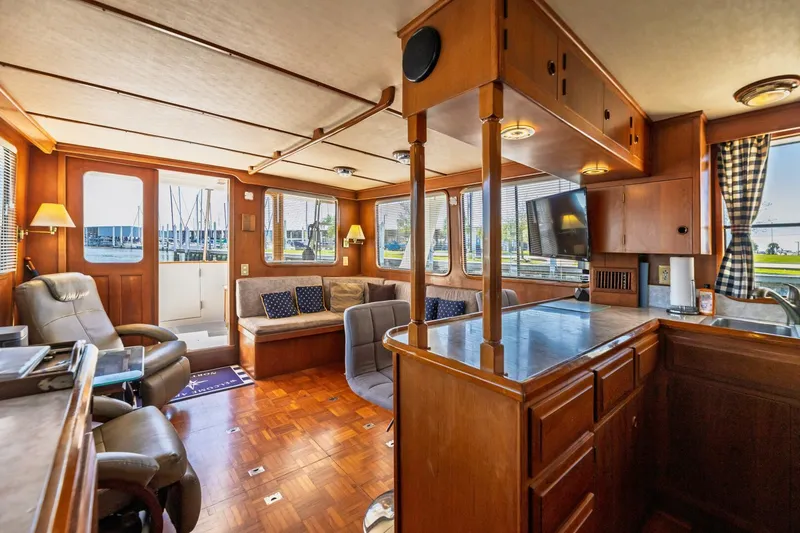 Slide: The Image of 1992 DeFever 49 Pilothouse interior with wood finish, seating area, and windows overlooking marina. - 5