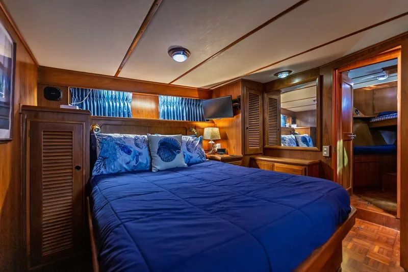 Slide: The Image of Luxurious 1992 DeFever 49 Pilothouse bedroom with blue bedding and wooden interior. - 8