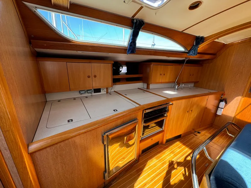 Slide: The Image of Interior of 2002 Jeanneau Sun Odyssey 45.2 yacht, featuring a wooden kitchen with ample storage. - 27
