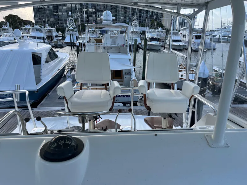 Slide: The Image of 1995 Hatteras 45 Convertible yacht helm with white captain chairs in a marina setting. - 10