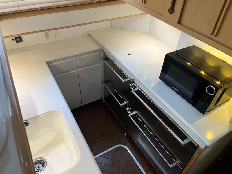 Slide: The Image of Compact kitchen area in a 1995 Hatteras 45 Convertible yacht with microwave and sink. - 12