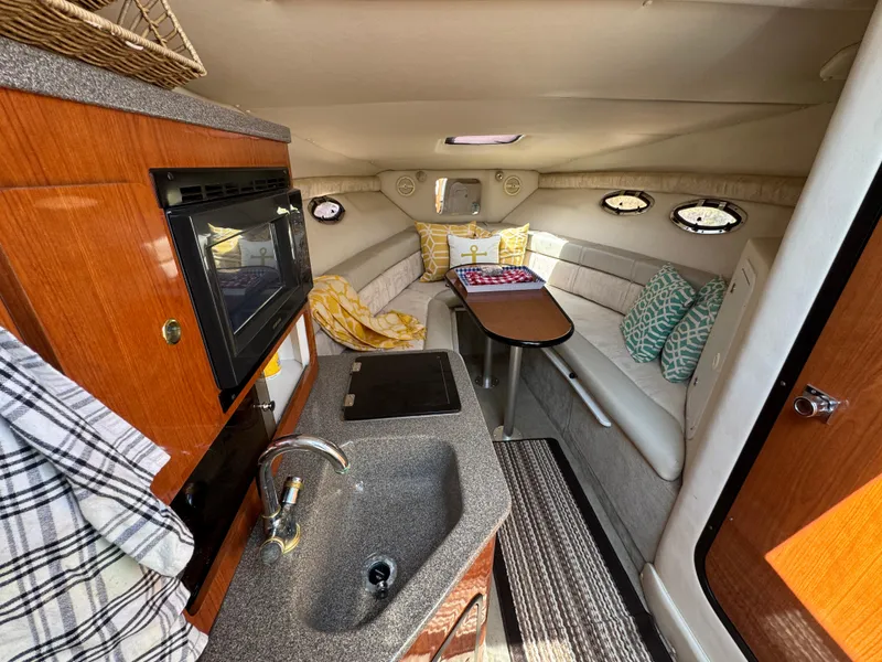 Slide: The Image of 2003 Crownline 262 CR cabin interior with kitchenette, seating area, and cozy decor. - 14
