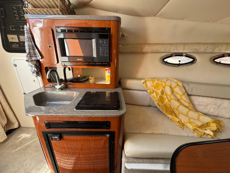 Slide: The Image of 2003 Crownline 262 CR cabin interior with kitchenette, microwave, sink, and cozy seating area. - 17