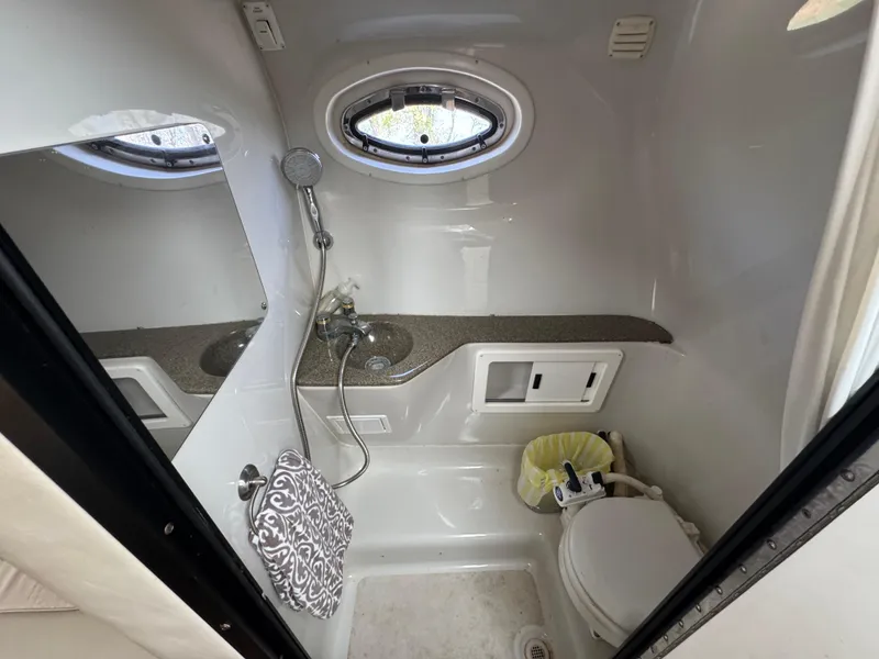Slide: The Image of 2003 Crownline 262 CR boat bathroom with sink, toilet, and porthole window. - 19