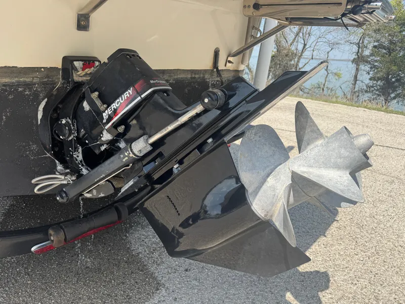 Slide: The Image of 2003 Crownline 262 CR boat with Mercury outboard motor and propeller, parked on pavement. - 5