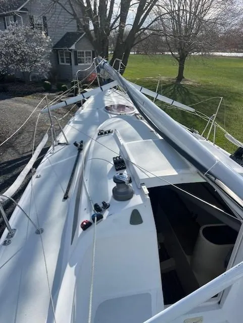 Slide: The Image of 2007 Columbia 32 sailboat deck with rigging, docked near a house and trees. - 12