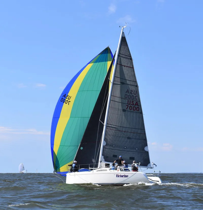 Slide: The Image of Sailing boat Columbia 32, 2007 model, with colorful spinnaker on open water. - 2