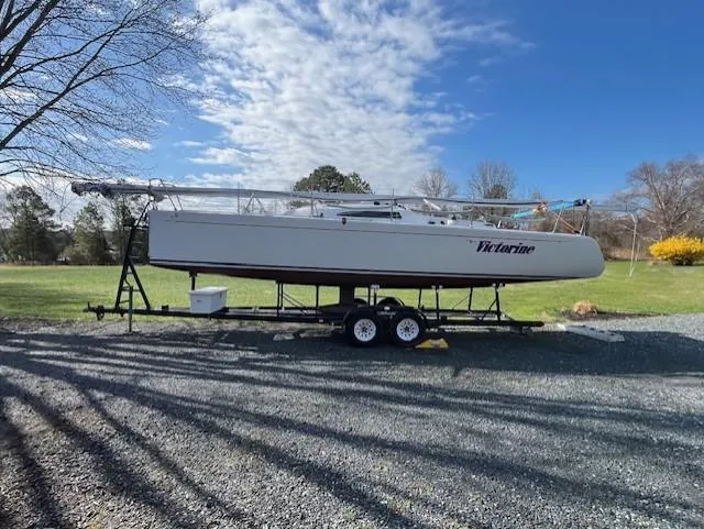 Slide: The Image of 2007 Columbia 32 sailboat on trailer, parked on gravel under a blue sky. - 8