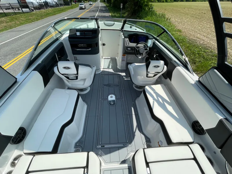 Slide: The Image of 2024 Chaparral 250 OSX boat interior with seating and steering console on a sunny day. - 41