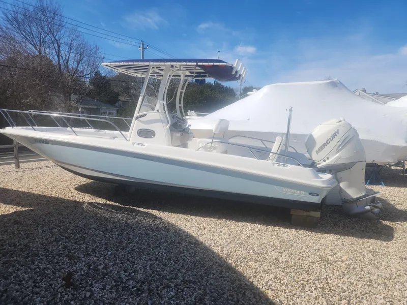 Slide: The Image of 2015 Boston Whaler 240 Dauntless boat on gravel, featuring a Mercury outboard motor. - 1