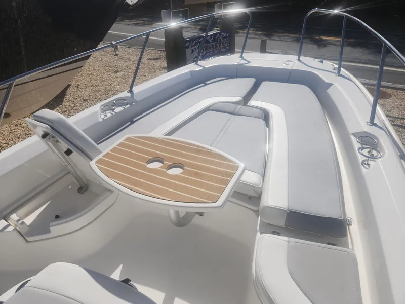 Slide: The Image of 2015 Boston Whaler 240 Dauntless boat interior with cushioned seating and wooden table. - 12