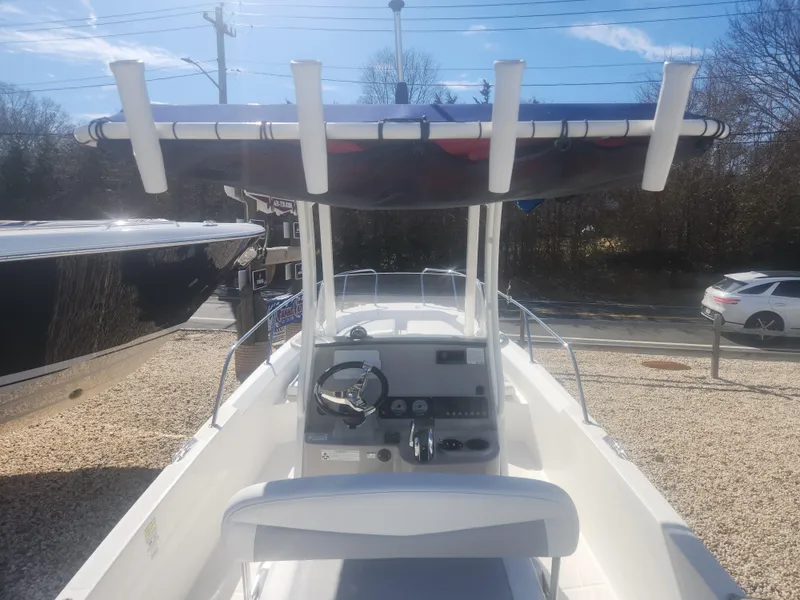 Slide: The Image of 2015 Boston Whaler 240 Dauntless boat with T-top and console, parked on gravel. - 6