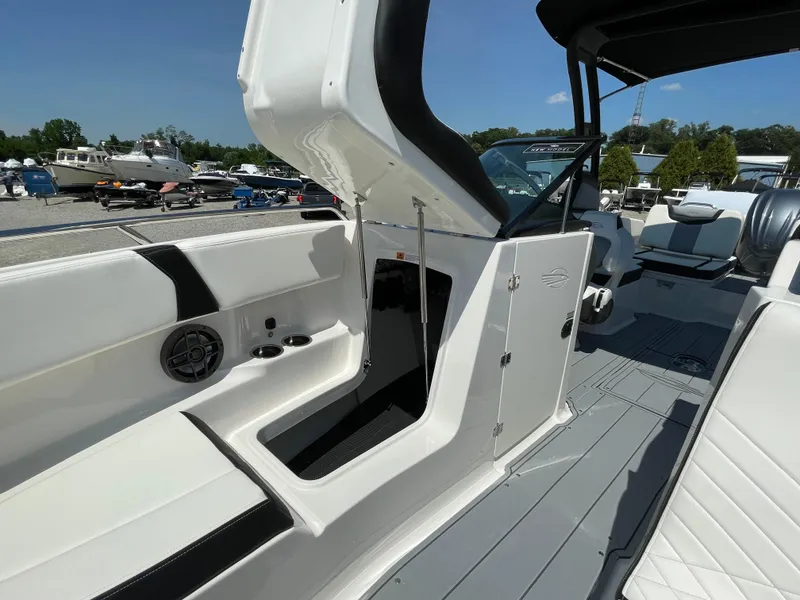Slide: The Image of 2024 Chaparral 250 OSX boat interior with open storage compartment and seating area. - 17