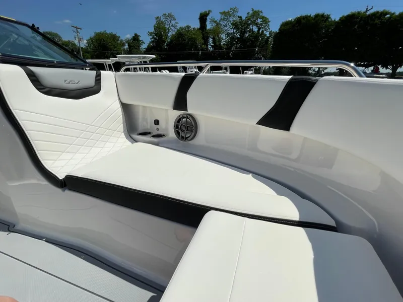 Slide: The Image of 2024 Chaparral 250 OSX boat interior with white and black seating under clear blue sky. - 12