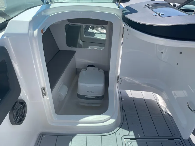 Slide: The Image of 2024 Chaparral 250 OSX boat cabin with compact toilet and seating area. - 32