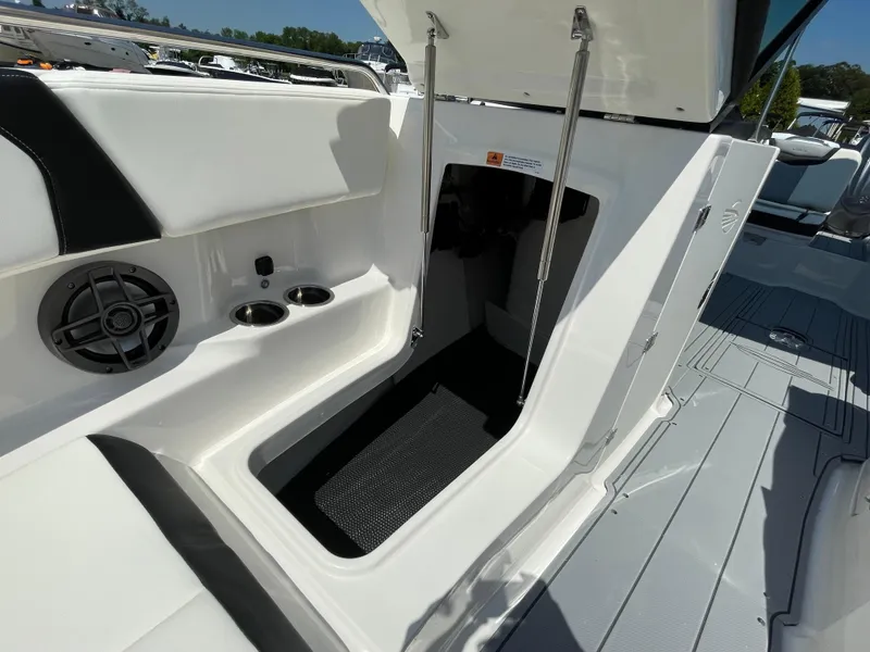 Slide: The Image of 2024 Chaparral 250 OSX boat interior with open storage compartment and cup holders. - 16