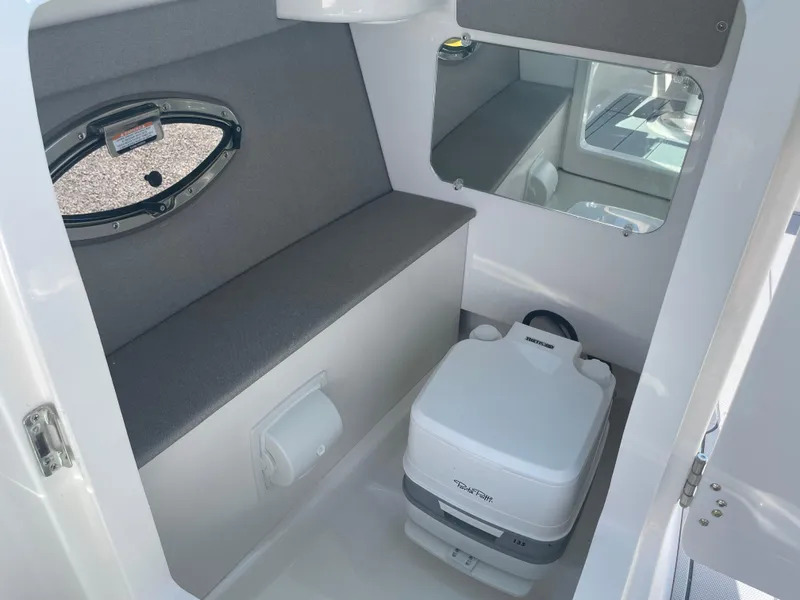 Slide: The Image of 2024 Chaparral 250 OSX boat interior with compact toilet and seating area. - 33