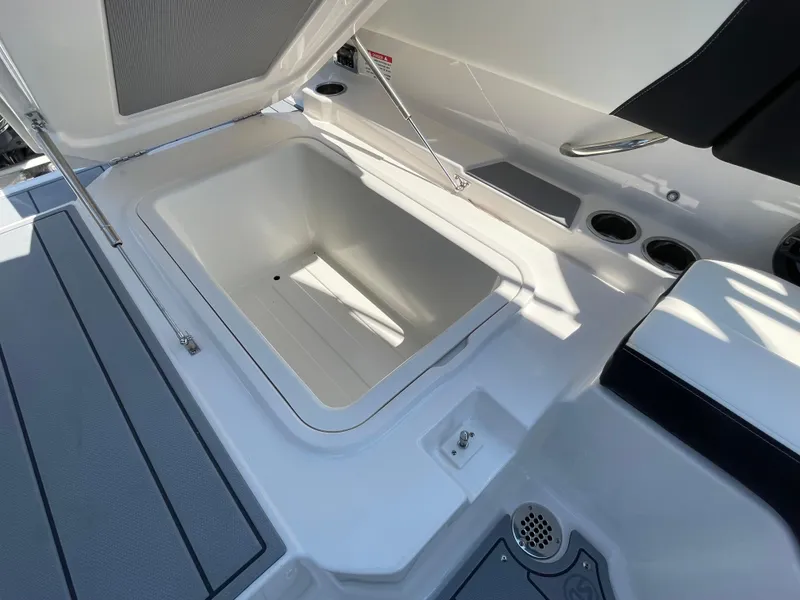 Slide: The Image of 2024 Chaparral 250 OSX boat storage compartment with open lid, showcasing spacious interior. - 47