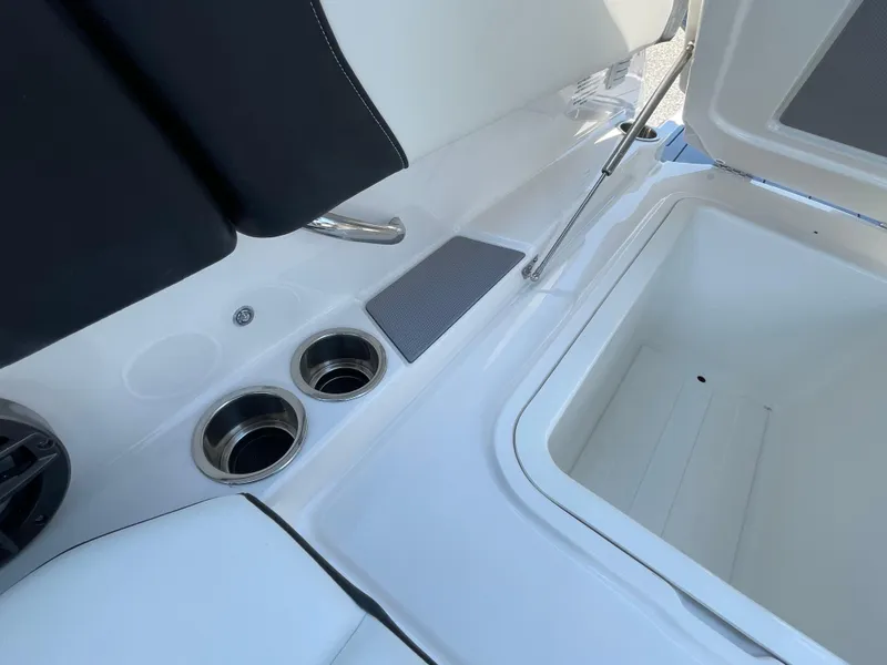 Slide: The Image of 2024 Chaparral 250 OSX boat interior with cup holders and storage compartment. - 49