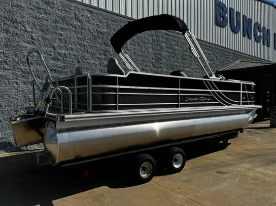 Slide: The Image of 2025 South Bay 224FCR LE pontoon boat on trailer, parked outside a building. - 10