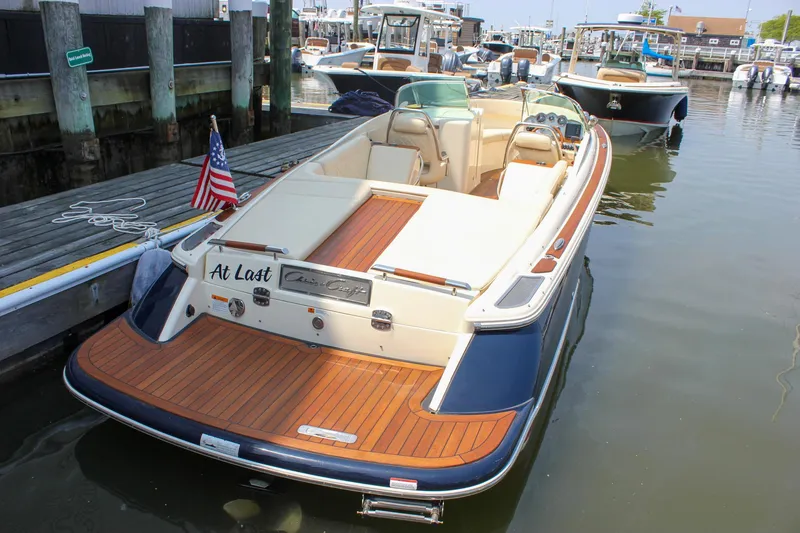 Slide: The Image of 2016 Chris-Craft Launch 25 boat docked, featuring elegant wood deck and American flag. - 1