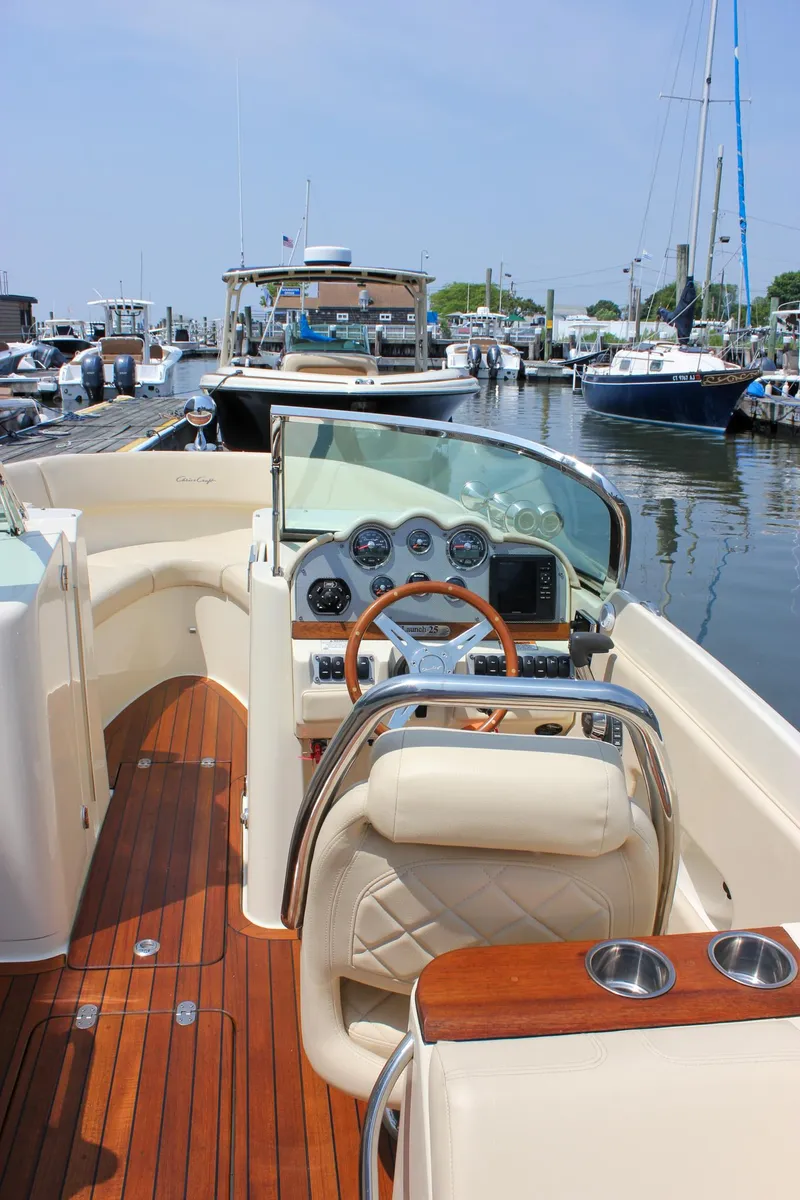 Slide: The Image of 2016 Chris-Craft Launch 25 boat interior with wooden deck and steering wheel at marina. - 12