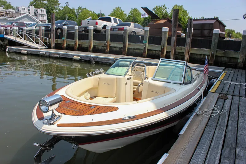 Slide: The Image of 2016 Chris-Craft Launch 25 boat docked at a marina, featuring elegant design and wood accents. - 2