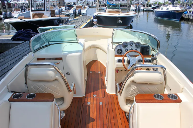 Slide: The Image of 2016 Chris-Craft Launch 25 boat interior with wooden deck and luxurious seating at a marina. - 29