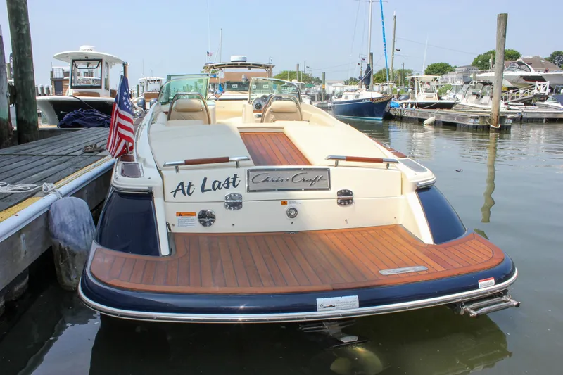 Slide: The Image of 2016 Chris-Craft Launch 25 boat docked, featuring elegant wood deck and American flag. - 33