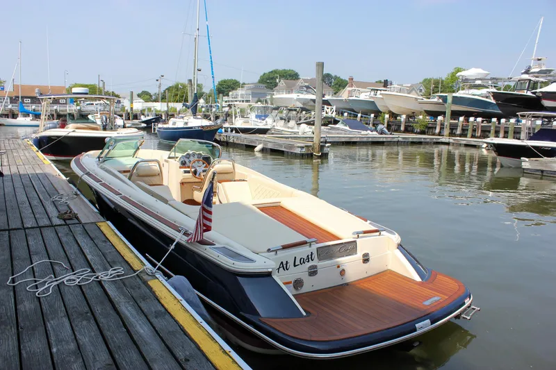 Slide: The Image of 2016 Chris-Craft Launch 25 boat docked in a marina, featuring elegant design and wooden deck. - 37