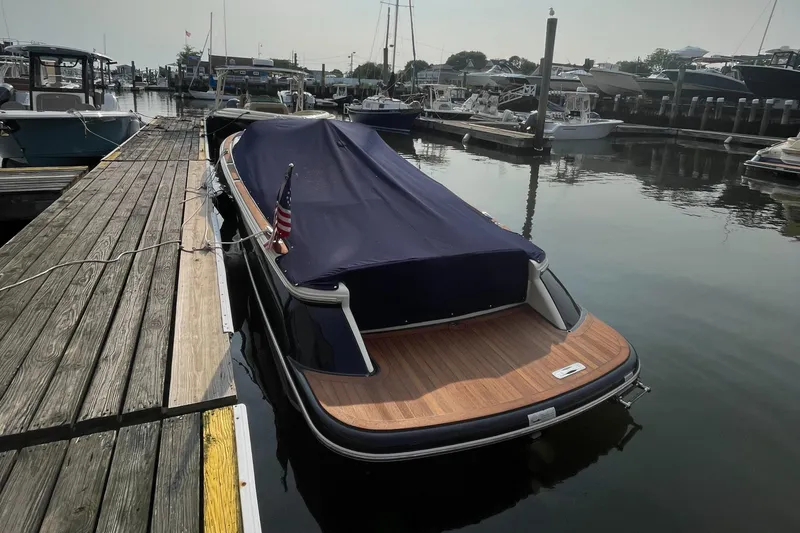Slide: The Image of 2016 Chris-Craft Launch 25 boat docked with cover, featuring wooden deck and American flag. - 4