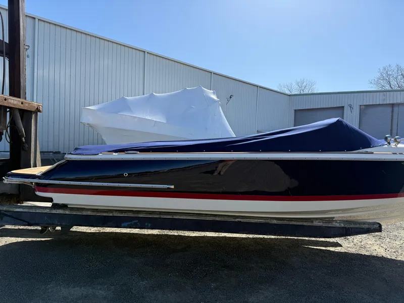 Slide: The Image of 2016 Chris-Craft Launch 25 boat with cover, parked outdoors near a warehouse. - 44