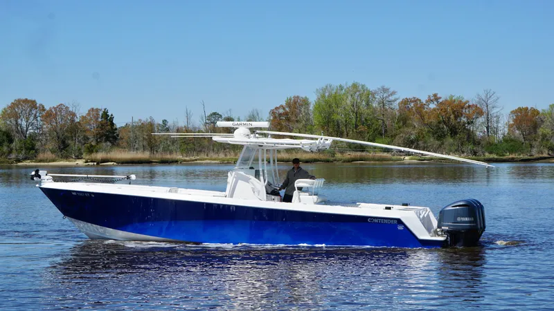 Slide: The Image of 2015 Contender 35 ST boat on calm water, blue hull, outboard engines, clear sky. - 4